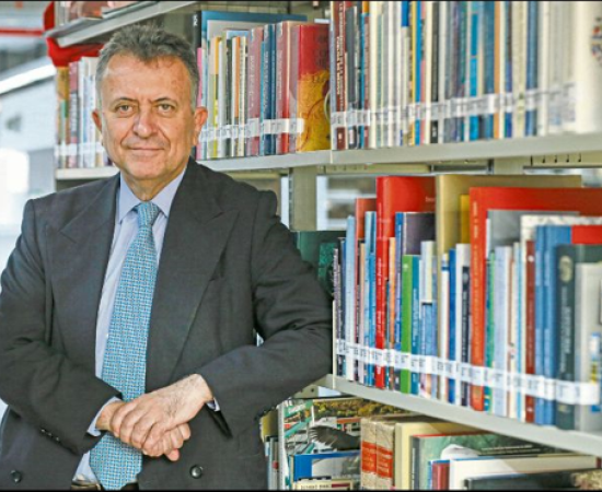 Una persona posando a lado de varios libros